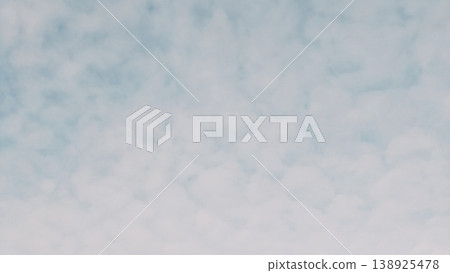 Soft blue sky covered with a pattern of white altocumulus clouds. A peaceful, textured background of natural morning light and high-altitude atmosphere. Soft blue sky covered with a pattern of white altocumulus clouds. A peaceful, textured background of natural morning light and high-altitude atmosphere. 138925478