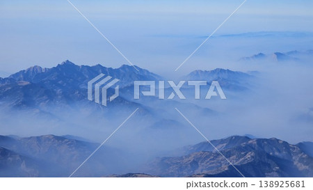 The sky is blue and the mountains are covered in fog The sky is blue and the mountains are covered in fog 138925681