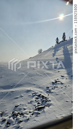 Snowy mountain with a bright sun shining on it Snowy mountain with a bright sun shining on it 138925800