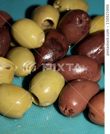 Sliced and chopped mixed olives on a blue background Sliced and chopped mixed olives on a blue background 138925866