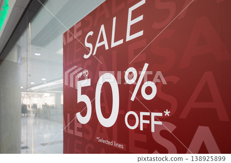 Red sale sign on store window offering up to fifty percent off Red sale sign on store window offering up to fifty percent off 138925899