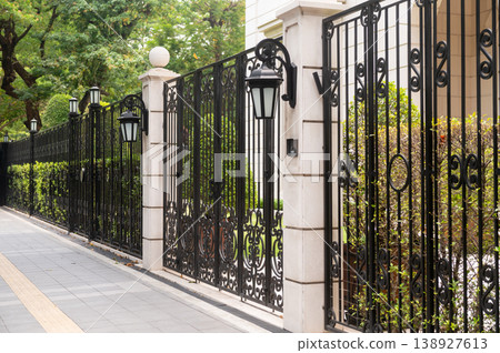 Elegant wrought iron fence beside sidewalk 138927613