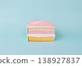 Piece of multi-layered pastel cake on light blue background 138927837