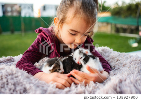 Little girl holding newborn kittens showing love and care 138927900
