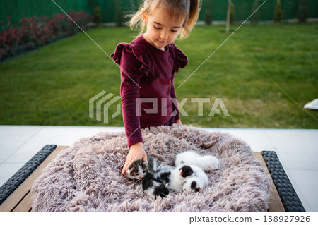 Girl bonding with newborn kittens on fluffy blanket outdoors 138927926