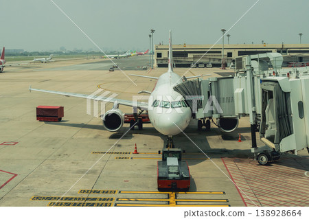 Airplane at Terminal Gate with Jet Bridge Connecting for Passengers at Busy Airport on Clear Day in Modern Travel Environment 138928664