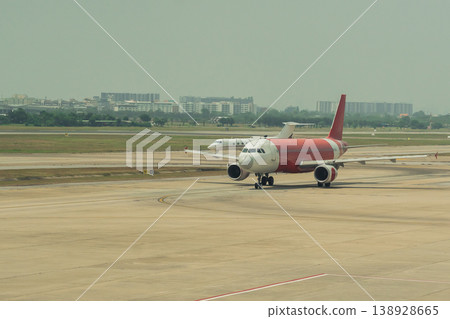Airplane on Runway at Airport with Clear Sky and Buildings in Background, Travel Transportation and Aviation Concept in Urban Environment 138928665