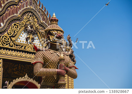 Majestic temple guardian statue with ornate details and vibrant colors against a clear blue sky, showcasing intricate craftsmanship and cultural heritage Majestic temple guardian statue with ornate details and vibrant colors against a clear blue sky, showcasing intricate craftsmanship and cultural heritage 138928667