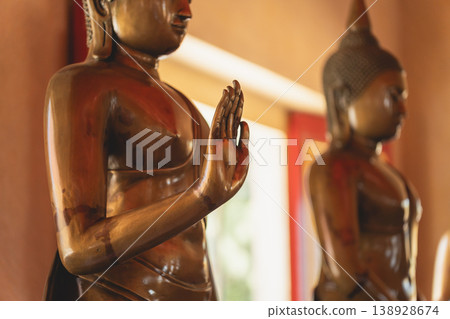 Serene Bronze Buddha Statues in Tranquil Setting with Decorative Details and Natural Light Illuminating the Peaceful Space 138928674