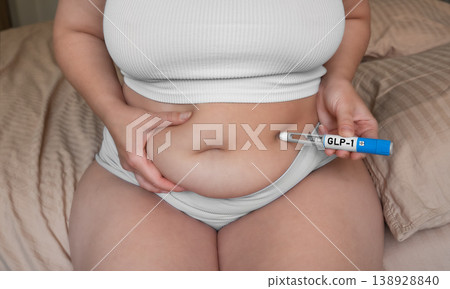 Woman injecting GLP-1 pen into abdomen, weight loss and diabetes treatment concept 138928840