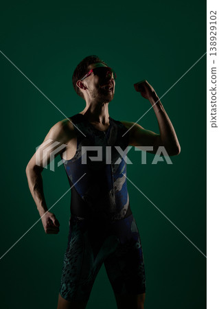 Male athlete celebrating with clenched fist and raised arm in studio lighting Male athlete celebrating with clenched fist and raised arm in studio lighting 138929102