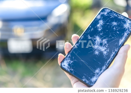 A car in the background of a smartphone with a cracked screen 138929236