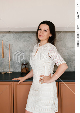 Elegant Lady in White Dress standing near Kitchen Counter Elegant Lady in White Dress standing near Kitchen Counter 138930027