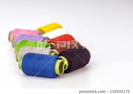 Vibrant Assorted Thread Spools with Lime Green Tape Arranged Diagonally on Clean White Background 138930175