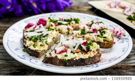 Egg salad open sandwiches with radish and chives on rye bread 138930980