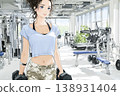 一位年輕女子在健身房裡舉著啞鈴行走的插圖。 138931404