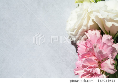 Fresh pink carnations and white eustomas on a light textured background with sunlight, top view. Fresh pink carnations and white eustomas on a light textured background with sunlight, top view. 138931653