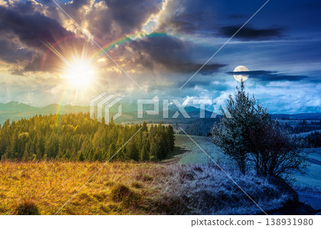 day meet night. mountain landscape on autumn equinox. sun and moon over green nature of carpathian mountains with fir forest. view of a scenery with rolling hills under epic sky. pasture near woods 138931980
