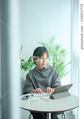 A woman with blonde and blue hair is using a tablet indoors. A woman with blonde and blue hair is using a tablet indoors. 138933778