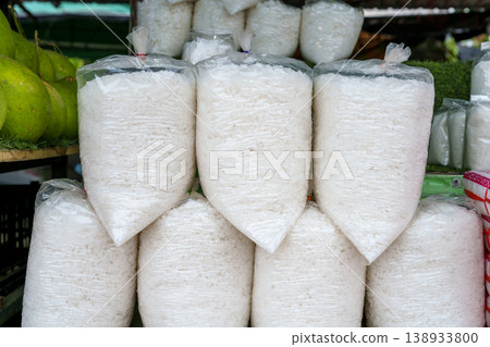 White sea salt grains packed in clear plastic bags stacked for sale at a local outdoor market. Traditional food seasoning and grocery trade in Southeast Asia with green pomelo fruit on the side. White sea salt grains packed in clear plastic bags stacked for sale at a local outdoor market. Traditional food seasoning and grocery trade in Southeast Asia with green pomelo fruit on the side. 138933800