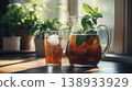 Refreshing Homemade Iced Tea with Fresh Mint in a Glass Pitcher and Tumbler on a Sunny Windowsill 138933929