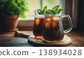 Two Glass Pitchers of Refreshing Iced Tea with Fresh Mint and Ice Cubes on a Wooden Board near Window 138934028
