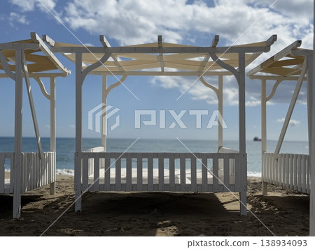 Beach cabana with wooden structure and view of ocean under cloudy sky, ideal as background 138934093