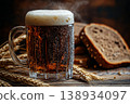 Traditional Cold Kvass in a Glass Mug with Rye Bread and Barley Ears on a Wooden Background 138934097