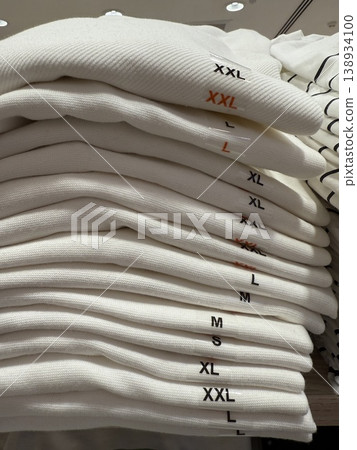 Folded sweaters in various sizes stacked neatly on a shelf, suitable as retail background 138934100