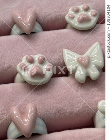 Pink plush background with ceramic cat paw and heart-shaped decorations in cute arrangement Pink plush background with ceramic cat paw and heart-shaped decorations in cute arrangement 138934104
