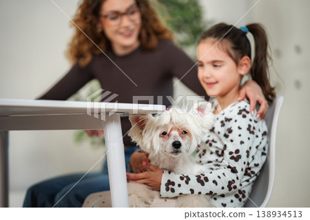 Mother and daughter bonding with their white pet dog Mother and daughter bonding with their white pet dog 138934513