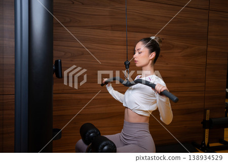 Woman training back muscles with lat pulldown machine 138934529
