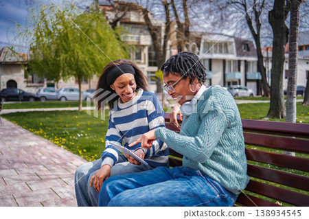 Two young adult friends pointing at a digital tablet 138934545