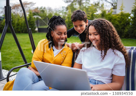 African American family bonding outdoors enjoying laptop together 138934550