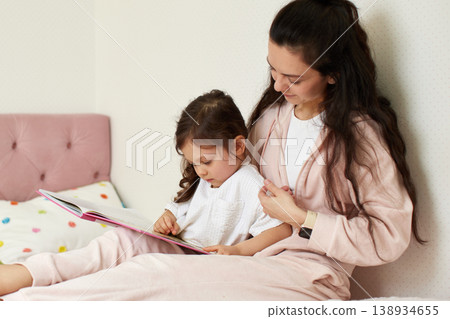 Young mother spending quality time with her child, reading a bedtime story together at home. Family bonding and education concept Young mother spending quality time with her child, reading a bedtime story together at home. Family bonding and education concept 138934655