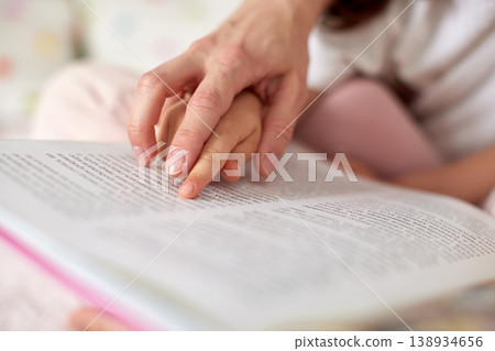 Parent and child hands pointing at text in an open book, symbolizing family literacy, education, and childhood learning Parent and child hands pointing at text in an open book, symbolizing family literacy, education, and childhood learning 138934656