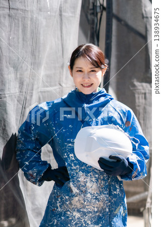 一位面帶微笑的女油漆工,手持安全帽。建築油漆、維護、技術工人、現場女性、戶外。 一位面帶微笑的女油漆工,手持安全帽。建築油漆、維護、技術工人、現場女性、戶外。 138934675