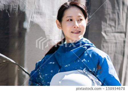 一位面帶微笑的女油漆工,手持安全帽。建築油漆、維護、技術工人、現場女性、戶外。 一位面帶微笑的女油漆工,手持安全帽。建築油漆、維護、技術工人、現場女性、戶外。 138934678
