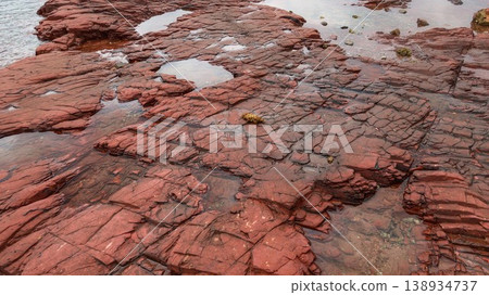 Layered deep red sedimentary rock formations with fractures and water pools in the seaside which is a remote coastal spots in Hung Shek Mun (Red Stone Gate), Plover Cove Country Park, Hong Kong Layered deep red sedimentary rock formations with fractures and water pools in the seaside which is a remote coastal spots in Hung Shek Mun (Red Stone Gate), Plover Cove Country Park, Hong Kong 138934737