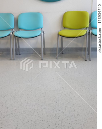 Phone photo of blue and green chairs in a hospital waiting area. Calm and organized interior scene showing seating, healthcare environment, and functional design. Phone photo of blue and green chairs in a hospital waiting area. Calm and organized interior scene showing seating, healthcare environment, and functional design. 138934740