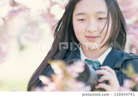 A high school girl with a camera under a cherry tree. Spring scenery. Photography club. Hobby. Student. Portrait. A high school girl with a camera under a cherry tree. Spring scenery. Photography club. Hobby. Student. Portrait. 138934741