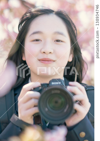 A high school girl with a camera under a cherry tree. Spring scenery. Photography club. Hobby. Student. Portrait. A high school girl with a camera under a cherry tree. Spring scenery. Photography club. Hobby. Student. Portrait. 138934746