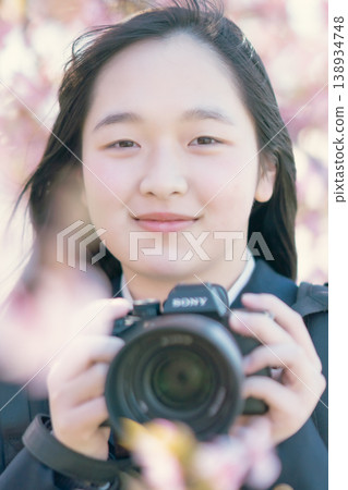 A high school girl with a camera under a cherry tree. Spring scenery. Photography club. Hobby. Student. Portrait. A high school girl with a camera under a cherry tree. Spring scenery. Photography club. Hobby. Student. Portrait. 138934748