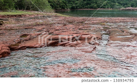 Layered deep red sedimentary rock formations with fractures and water pools in the seaside which is a remote coastal spots in Hung Shek Mun (Red Stone Gate), Plover Cove Country Park, Hong Kong Layered deep red sedimentary rock formations with fractures and water pools in the seaside which is a remote coastal spots in Hung Shek Mun (Red Stone Gate), Plover Cove Country Park, Hong Kong 138934793