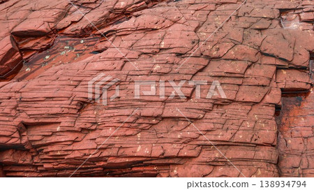 Layered deep red sedimentary rock formations with fractures and water pools in the seaside which is a remote coastal spots in Hung Shek Mun (Red Stone Gate), Plover Cove Country Park, Hong Kong Layered deep red sedimentary rock formations with fractures and water pools in the seaside which is a remote coastal spots in Hung Shek Mun (Red Stone Gate), Plover Cove Country Park, Hong Kong 138934794