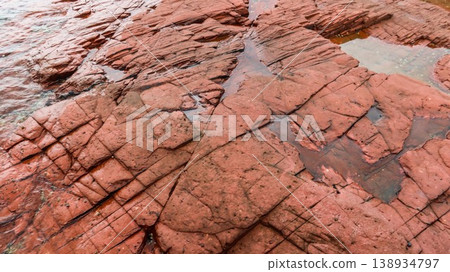 Layered deep red sedimentary rock formations with fractures and water pools in the seaside which is a remote coastal spots in Hung Shek Mun (Red Stone Gate), Plover Cove Country Park, Hong Kong Layered deep red sedimentary rock formations with fractures and water pools in the seaside which is a remote coastal spots in Hung Shek Mun (Red Stone Gate), Plover Cove Country Park, Hong Kong 138934797