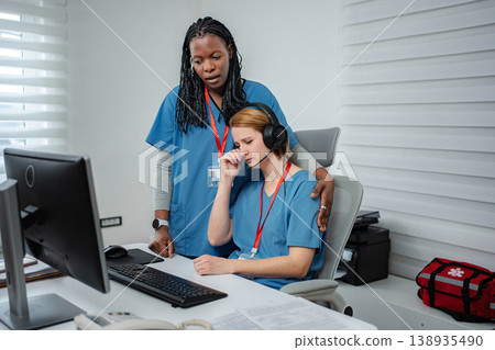Healthcare worker comforting distressed colleague crying at desk 138935490