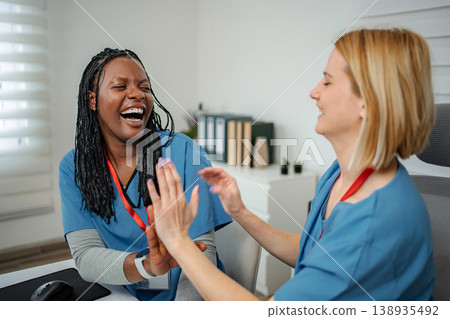 Happy medical professionals laughing and giving high five in clinic Happy medical professionals laughing and giving high five in clinic 138935492
