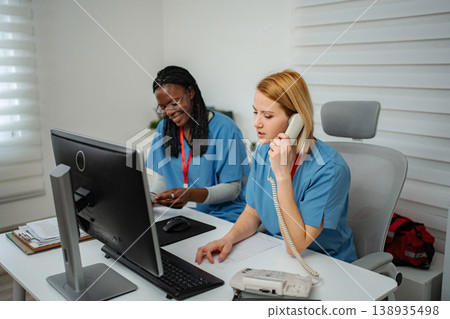 Medical receptionists collaborating on patient appointments and calls Medical receptionists collaborating on patient appointments and calls 138935498