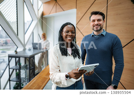 Diverse business professionals smiling, collaborating in modern office 138935504